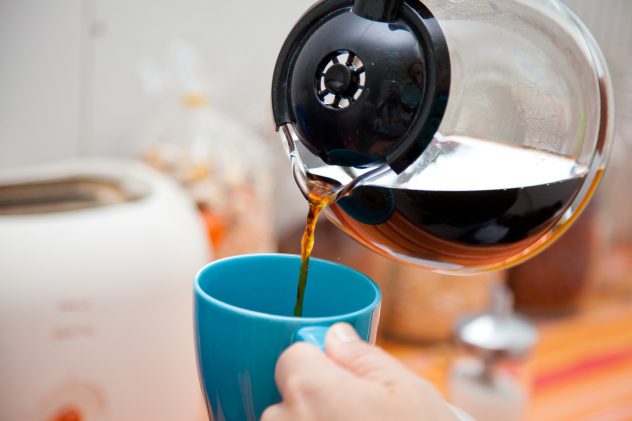 woman pouring coffee pot  into coffee mug