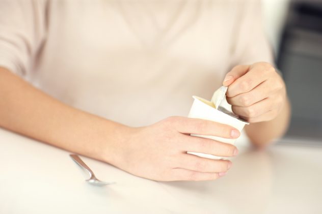 Woman opening yogurt plastic can yoghurt