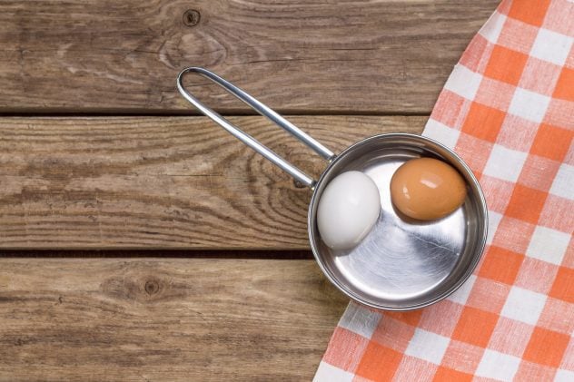 Two eggs in saucepan on wooden table