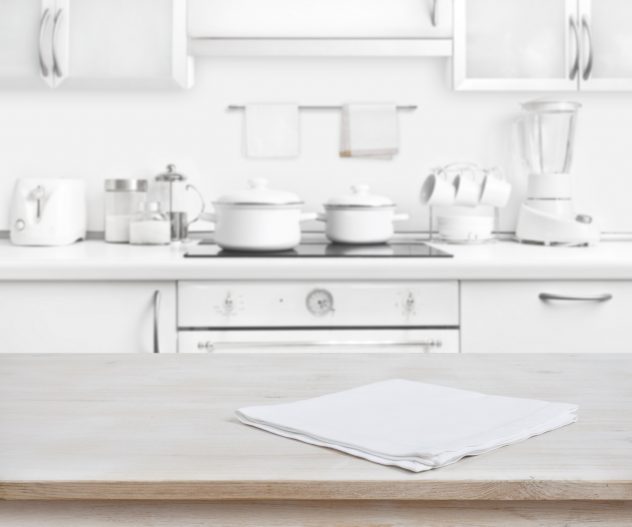 Wooden table with towel on blurred white modern kitchen background